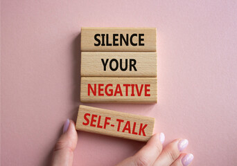 Silence your negative self-talk symbol. Concept words Silence your negative self-talk on wooden blocks. Doctor hand. Beautiful pink background. Psychology concept. Copy space.