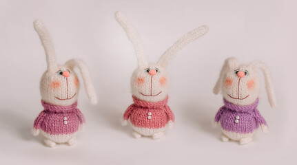 Handmade knitted bunnies stand against a white background. Postcard for congratulations on the New...