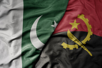 big waving realistic national colorful flag of pakistan and national flag of angola .