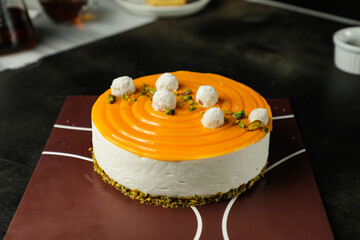 Mango Yogurt Cake topping with pistachio fork and flowers served in plate isolated on napkin side...