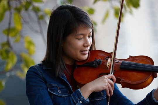 Young Asian female violin player practising outdoors