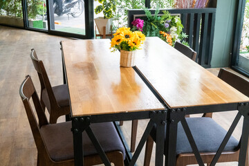 Sunflower in vase on wooden chairs and tables in restaurant or cafe.