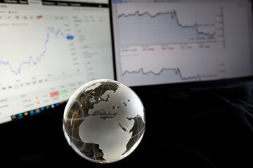 株価チャートとガラスの地球儀　世界経済のイメージ　Glass globe with graphs of stock prices	