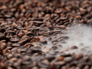 Close-up of roasted coffee beans with smoke. Coffee beans in smoke.
