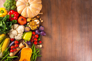 Autumn vegetable preparation dinner background. Food background with organic fresh farm raw veggies, pumpkin, corn, fruits, mushrooms, salad leaves, greenery, Ingredients for cooking with copy space.