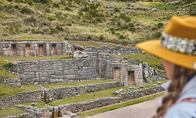 Beautiful tourist girl exploring Tambomachay Inca ruins near Cusco in Peru. Travel concept.