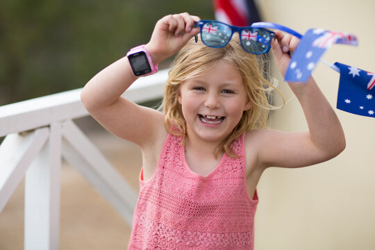 Child laughing holding Australian flag sunglasses