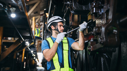 Fototapeta na wymiar Industrial engineers inspect and perform maintenance on the machines at factory machines. Teamwork in the Manufacturing Industry in the train garage.