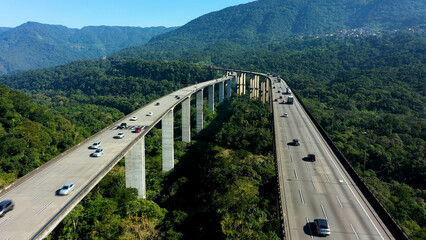 Aerial landscape of landmark highway road at green forest trees and mountains. Traffic at famous road way to brazilian south coast. Legendary engineering construction. Brazilian road landmark.