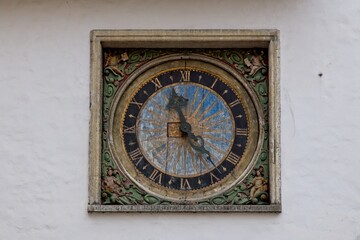 Decorative old street wall clock with paint peeling on a building.