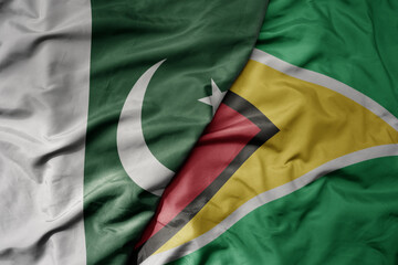 big waving realistic national colorful flag of pakistan and national flag of guyana .