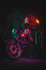 Young beautiful girl in black bodysuit is posing near the motorbike at night street concept. Woman motorbiker.