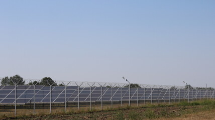 a complex of solar panels standing on a country field behind a wire fence, solar panels in operation, modern equipment used in the field of energy saving and alternative energy