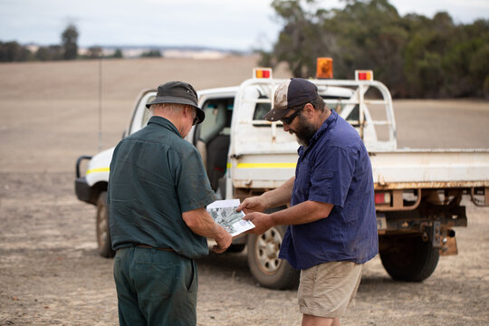 two men looking at map outdoors near work vehicle