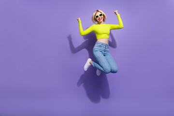 Photo of charming overjoyed girl wear trendy bright clothes celebrate success jump empty space isolated on purple color background