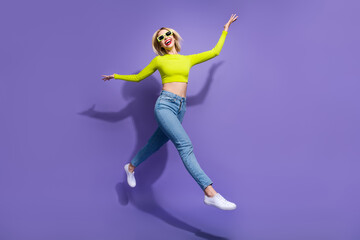 Full length photo of cheerful positive girl wear stylish clothes having fun going empty space isolated on purple color background