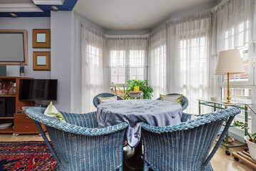 Living room with stretcher table surrounded by blue painted wicker armchairs