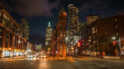 Dusk to night timelapse view of traffic around historic landmark Flatiron Building in Downtown Toronto, Ontario, Canada, zoom out.