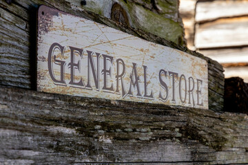 Retro vintage weathered rustic wooden general store sign hanging on exterior wall