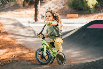 happy little boy skater style training with his bike on pump track circuit