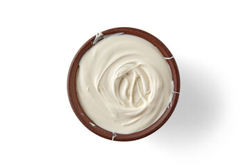 Greek yogurt sour cream in a brown clay bowl isolated on a white background. Top view with copy space
