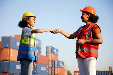 young female African factory workers or engineer fist bump for agreement or success at works in containers warehouse storage
