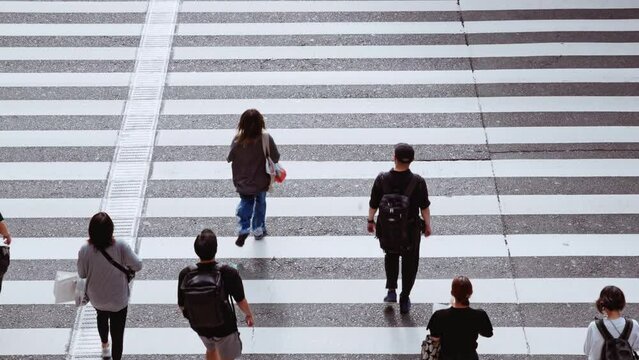 Crowded Japanese people, Asian traveler walk, run cross road at zebra crossing. Japan culture, Tokyo Osaka urban lifestyle, Asia transport, commuter transportation or city life concept. Slow motion