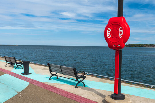 Two wooden benches on the Dunkirk, New York, USA city pier on Lake Erie along with a life ring case on a sunny fall day