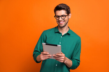 Photo of young intelligent businessman browsing tablet device analysis data information news changing isolated on orange color background