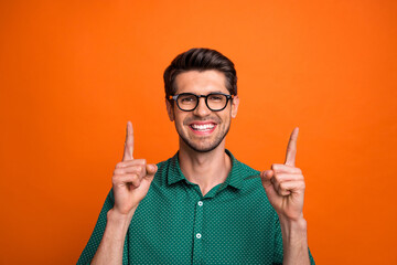 Photo of handsome cool guy wear green shirt typing pointing two fingers up empty space isolated orange color background