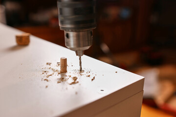 Drill holes for attaching furniture legs. Assembling cabinet furniture.