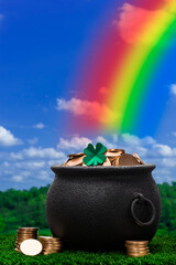 A black kettle pot full of gold coins and a single four leaf clover on top sitting in the grass, there is a rainbow coming out of the top of the pot. 