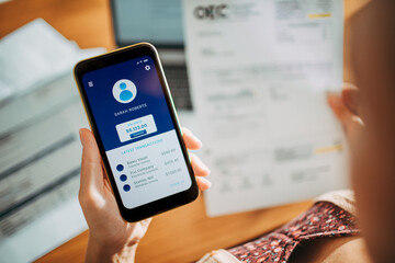 Young woman checking her profile on a bank app while paying bills at home
