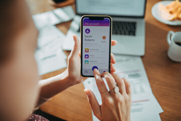 Young woman checking her profile on a bank app while paying bills at home