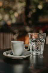 white cup of coffee on the table and a glass of water in a cafe