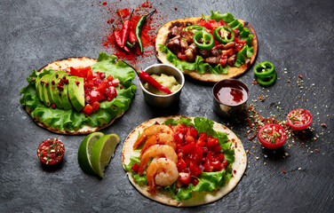 Tacos with salsa, vegetables and avocado on black background