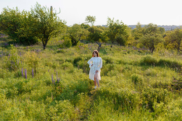 A woman walking around lupine flowers and a tree in a park
