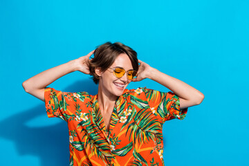 Portrait of positive lovely girl toothy smile hands touch head dancing enjoy free time isolated on blue color background