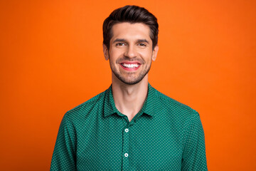 Photo of cheerful positive man dressed green shirt smiling showing white teeth isolated orange color background