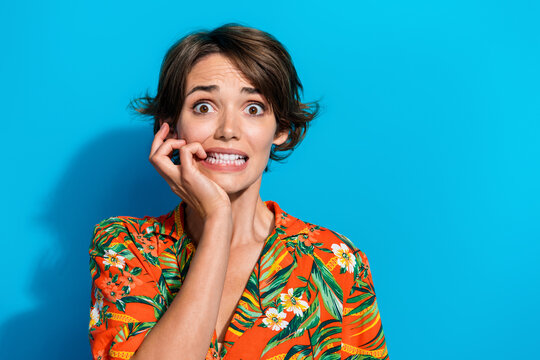 Photo of anxious embarrassed girl wear trendy clothes biting fingernails unexpected news empty space isolated on blue color background