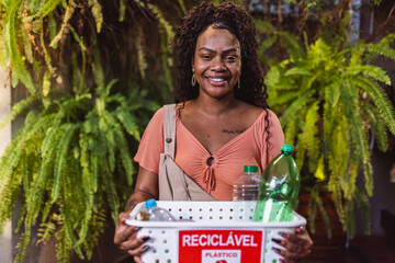 Young black woman holding a basket with plastic bottles for recycling.