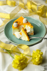 Mango Yogurt Cake slice topping with pistachio fork and flowers served in plate isolated on napkin side view cafe bake food