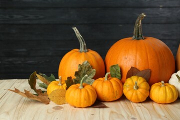 Thanksgiving day. Many different pumpkins and dry leaves on wooden table