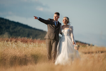 shot of a handsome young groom holding a jacket, photo in the middle of a field, the young man is...