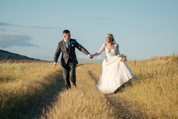 beautiful bride and groom running together, holding hands and being happy, wedding photo shoot in...