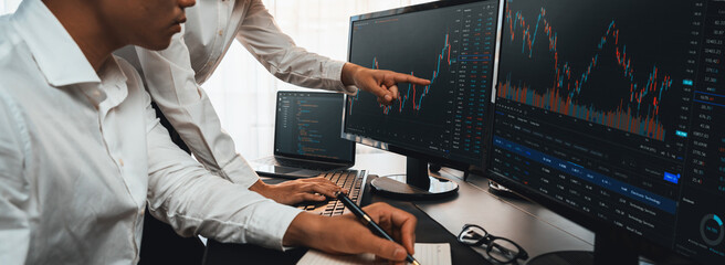 Group of traders discussing on office desk, monitoring stock market on monitor at office workplace. Businessman and broker analyzing stock graph together at stock trading company. Trailblazing - obrazy, fototapety, plakaty