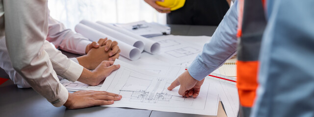 Engineer partner drawing and working on blueprint design together on office table for architectural...