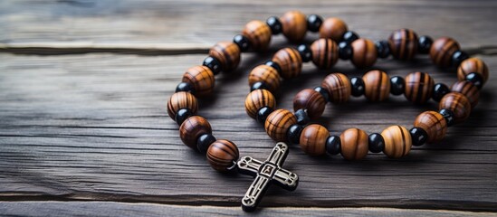 Wooden cross and black prayer beads against a light wooden background symbolizing National Christian day with focus on specific details