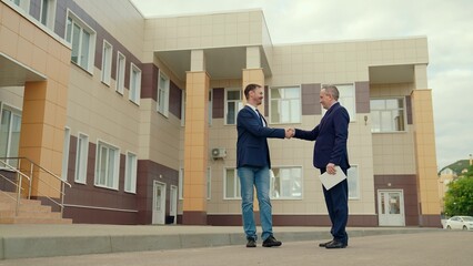 Businessmen in jackets greet on street with gesture of male hands. Politicians. Businessmen shaking hands, teamwork. Two men shaking hands, making successful contract agreement partnership cooperation
