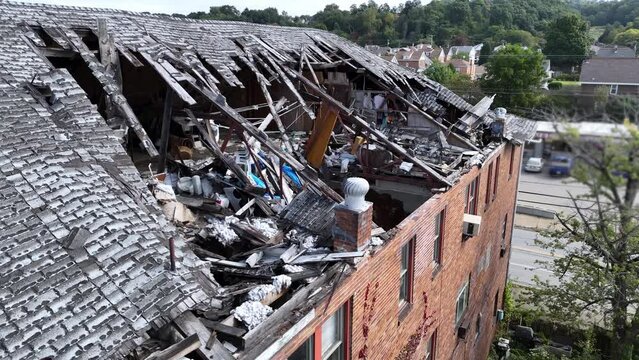 An aerial view of a collapsed roof on an old three story red brick industrial building.  	